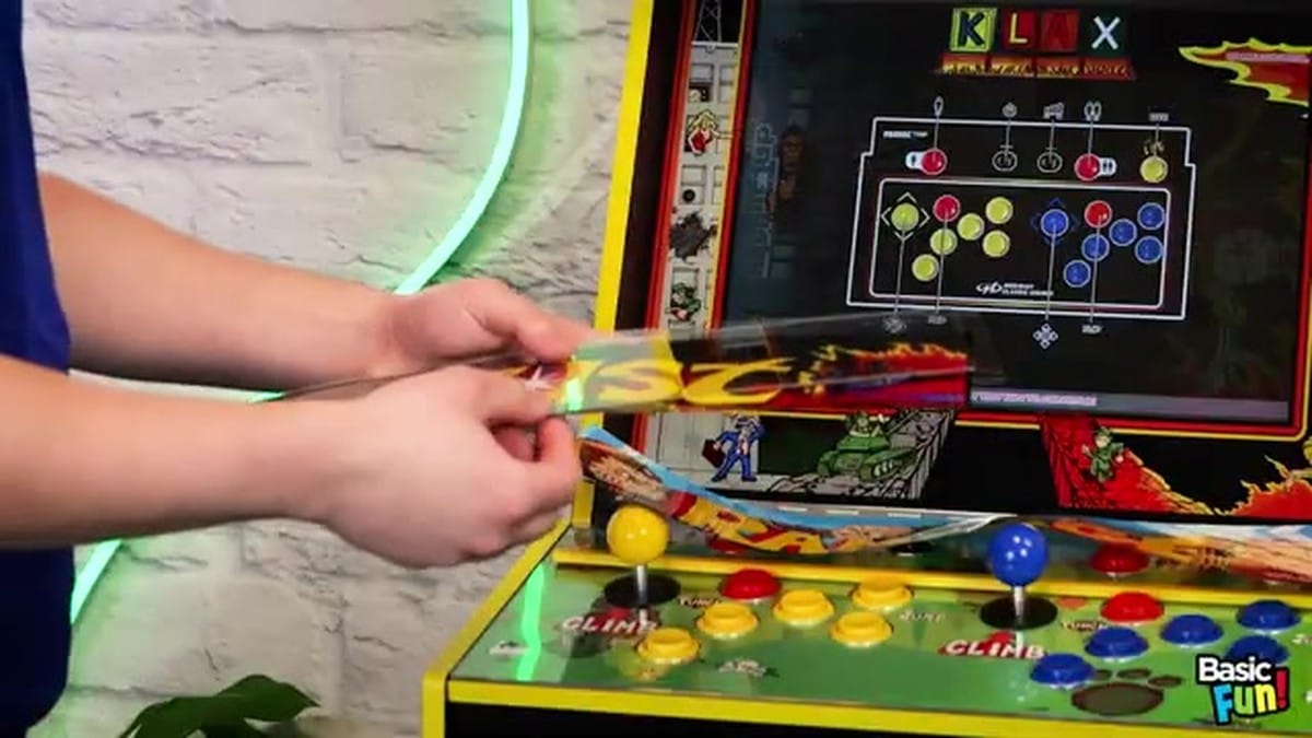 A person sliding a new Joust marquee into the top of the cabinet.